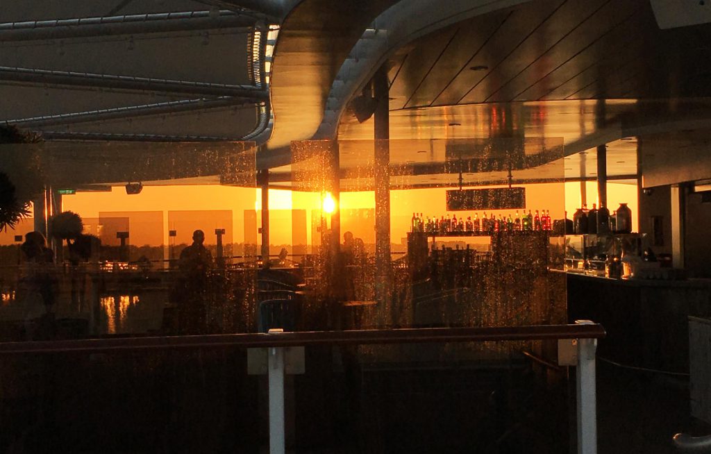 Blick durch die Bar auf den Sonnenuntergang an Bord der Neuen Mein Schiff 1