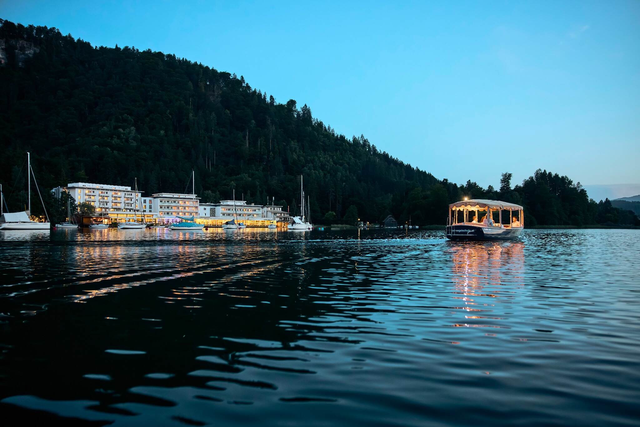 Beleuchteter Uferbereich des ROBINSON LANDSKRON in der blauen Abenddämmerung