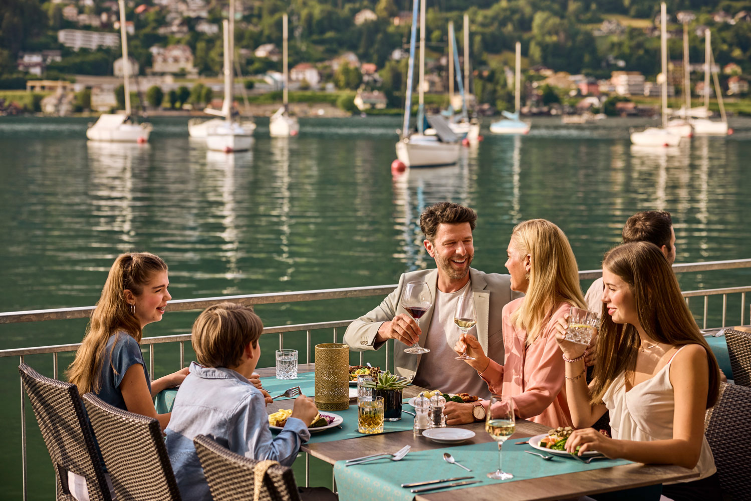 Gemeinsames Essen auf der Terrasse direkt am See mit Segelbooten im Hintergrund