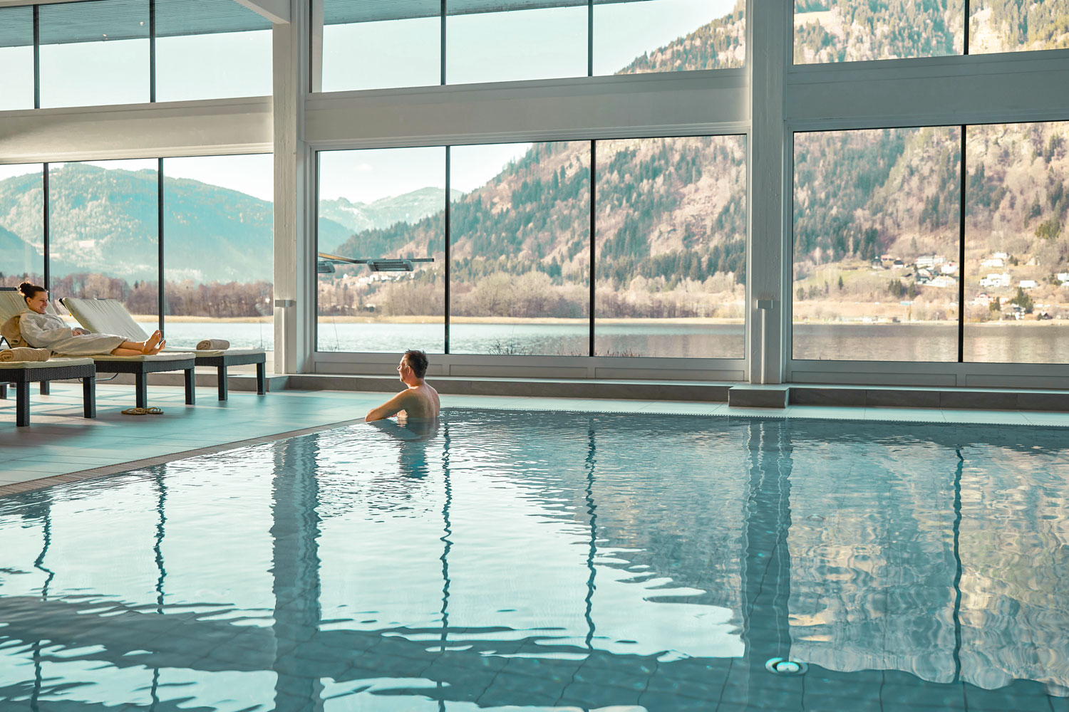 Innenpool mit großen Panoramafenstern und Blick auf den See
